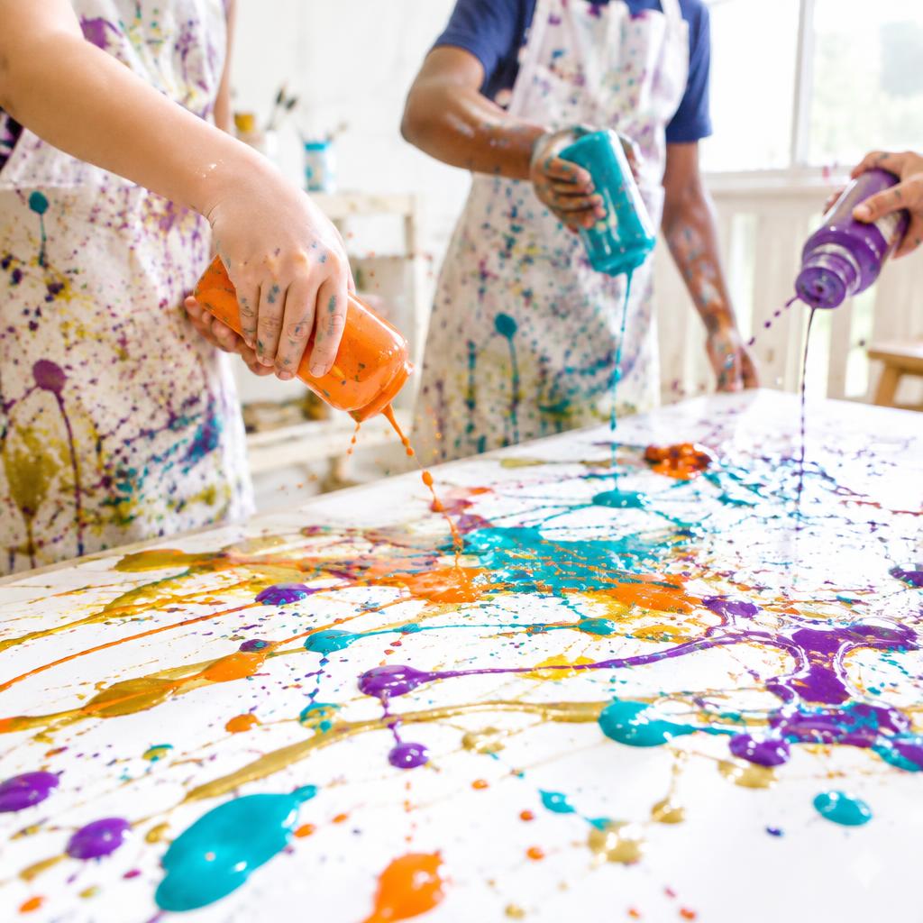Children splashing colorful paint onto a canvas